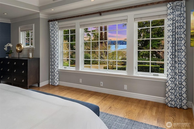 bedroom featuring multiple windows, crown molding, baseboards, and wood finished floors