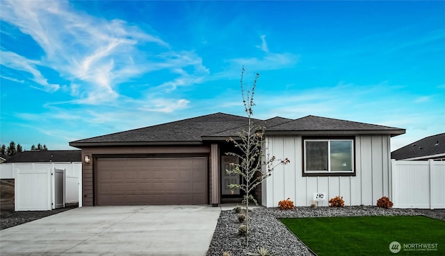 view of front of property featuring driveway, a shingled roof, an attached garage, fence, and board and batten siding