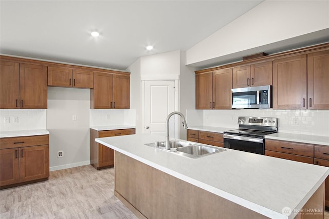 kitchen featuring brown cabinets, decorative backsplash, stainless steel appliances, and a sink