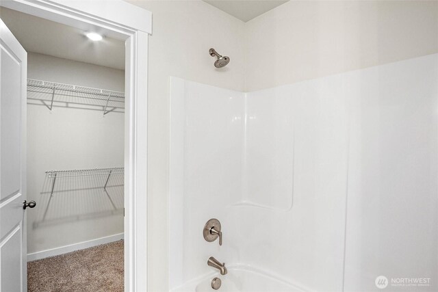 bathroom with baseboards, a spacious closet, and shower / tub combination