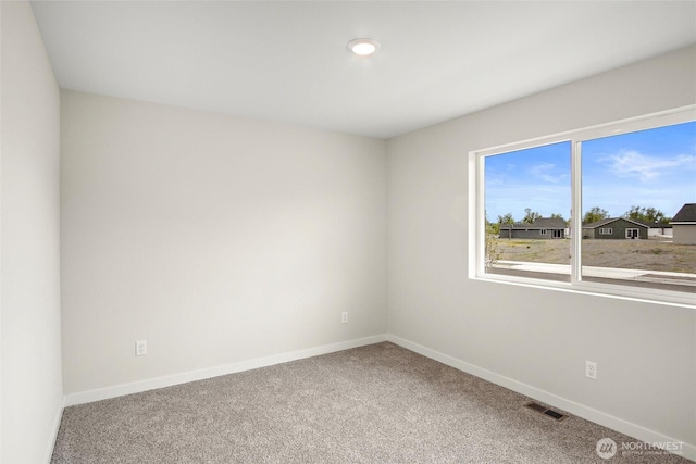 unfurnished room featuring carpet floors, visible vents, and baseboards