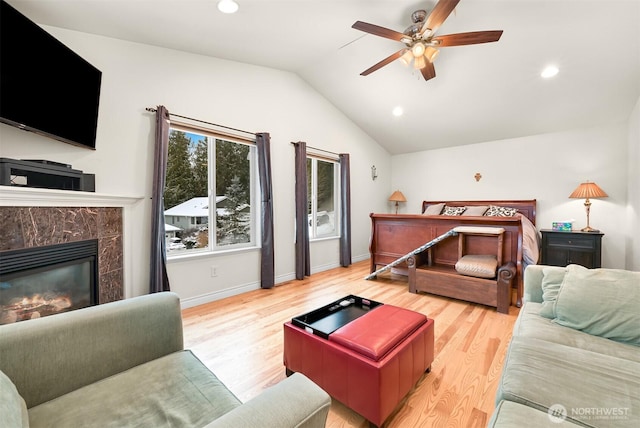 bedroom with a tiled fireplace, lofted ceiling, hardwood / wood-style floors, and ceiling fan