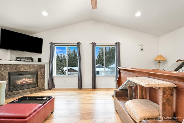 living room featuring a fireplace, light wood-type flooring, and vaulted ceiling