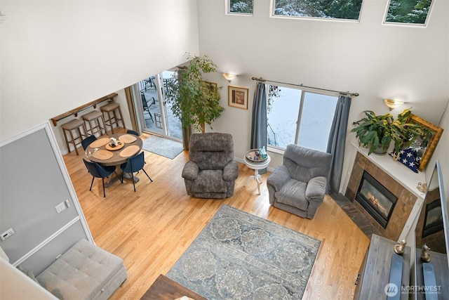 living room featuring a fireplace, wood-type flooring, and a towering ceiling