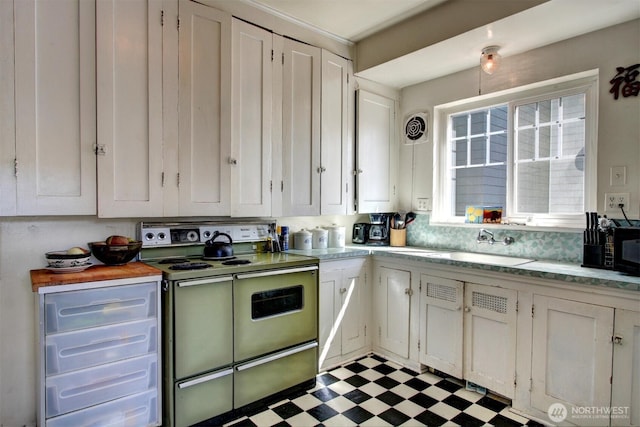 kitchen with white cabinets, range, dark floors, light countertops, and a sink