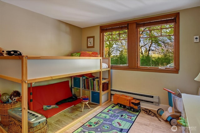 bedroom featuring multiple windows, a baseboard heating unit, and wood finished floors