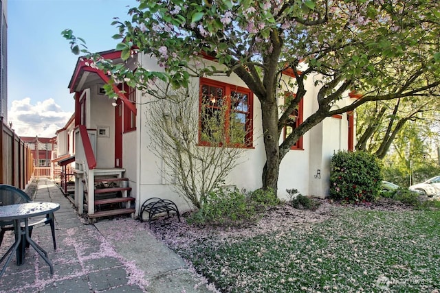 view of side of home featuring entry steps, fence, and stucco siding