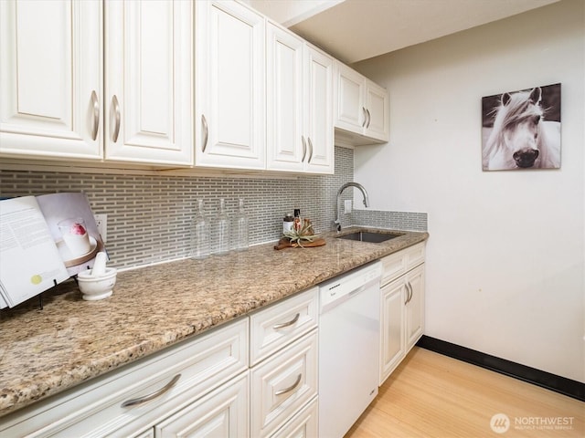 kitchen with sink, backsplash, light stone counters, dishwasher, and white cabinets