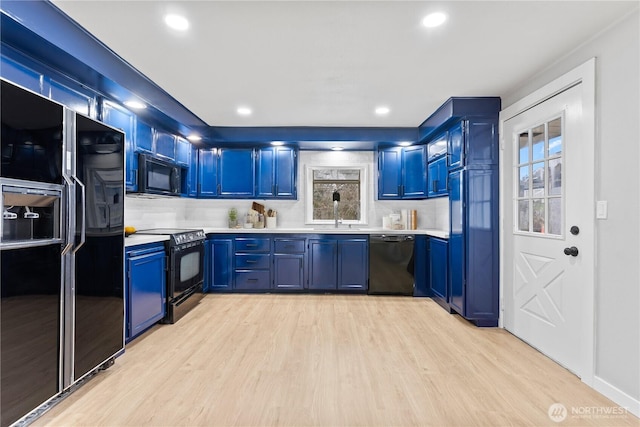 kitchen with blue cabinets, tasteful backsplash, black appliances, and light hardwood / wood-style floors