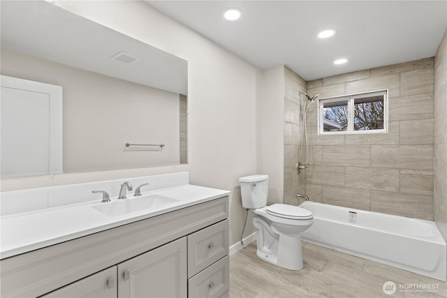 full bathroom featuring toilet, vanity, and tiled shower / bath