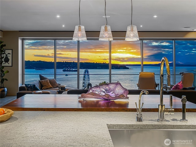 interior space with open floor plan, a water view, a sink, and recessed lighting