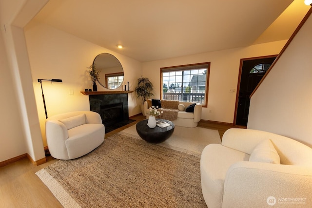 living room with hardwood / wood-style flooring, vaulted ceiling, and a fireplace