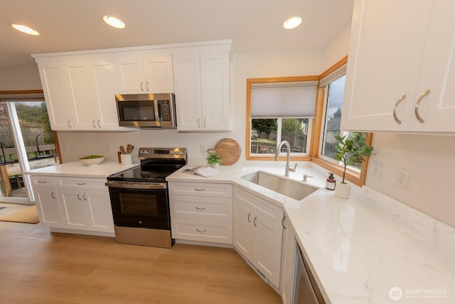 kitchen with white cabinetry, appliances with stainless steel finishes, sink, and a wealth of natural light