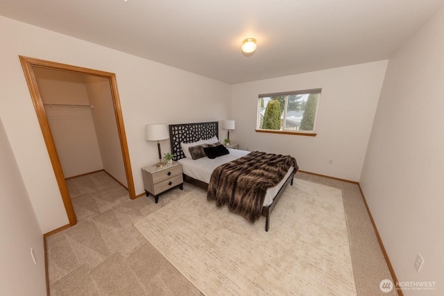 bedroom featuring light colored carpet and a walk in closet