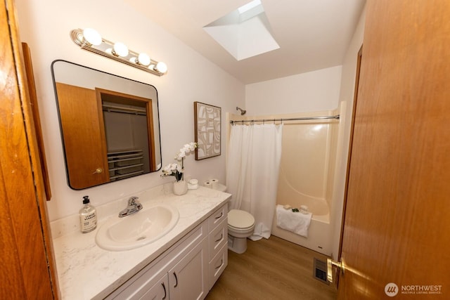 full bathroom featuring wood-type flooring, vanity, shower / bath combination with curtain, a skylight, and toilet