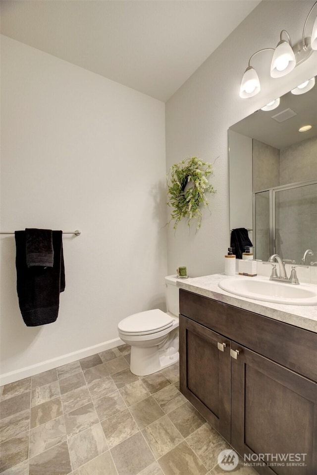 bathroom with baseboards, vanity, a shower stall, and toilet