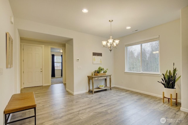 interior space with a notable chandelier, visible vents, light wood-type flooring, and baseboards