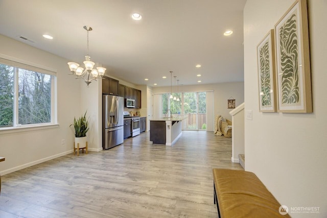 kitchen with an inviting chandelier, light wood-style floors, appliances with stainless steel finishes, and dark brown cabinetry