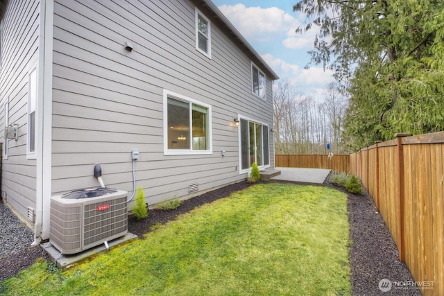 back of house with central AC unit, a lawn, and a fenced backyard