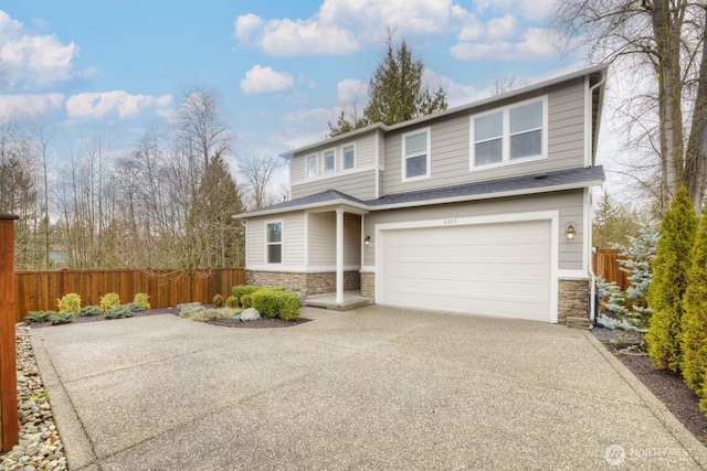 traditional home featuring a garage, stone siding, concrete driveway, and fence