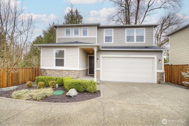 view of front of house featuring stone siding, driveway, an attached garage, and fence