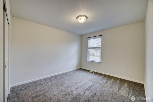 empty room with visible vents, baseboards, and dark carpet