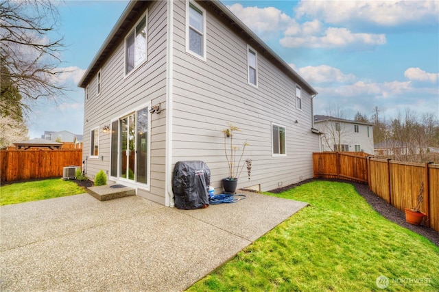 back of property with central air condition unit, a patio, a lawn, and a fenced backyard