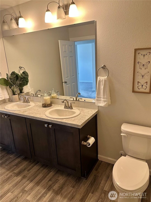 full bathroom featuring double vanity, toilet, wood finished floors, and a sink