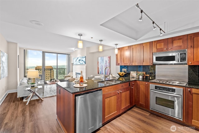 kitchen with sink, kitchen peninsula, appliances with stainless steel finishes, and pendant lighting