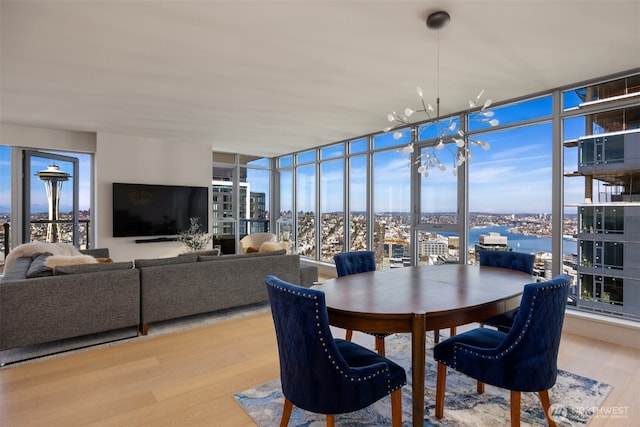 dining area featuring a healthy amount of sunlight, wood finished floors, floor to ceiling windows, and an inviting chandelier