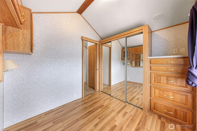 unfurnished bedroom featuring light wood-type flooring, vaulted ceiling, and a closet