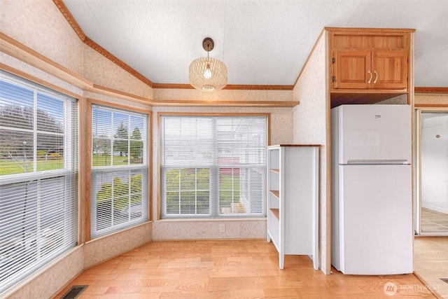 kitchen with light hardwood / wood-style floors, white refrigerator, crown molding, and decorative light fixtures