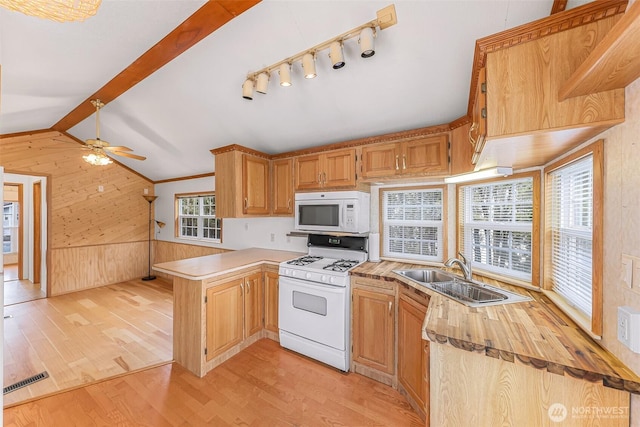 kitchen featuring wooden walls, white appliances, sink, light wood-type flooring, and kitchen peninsula