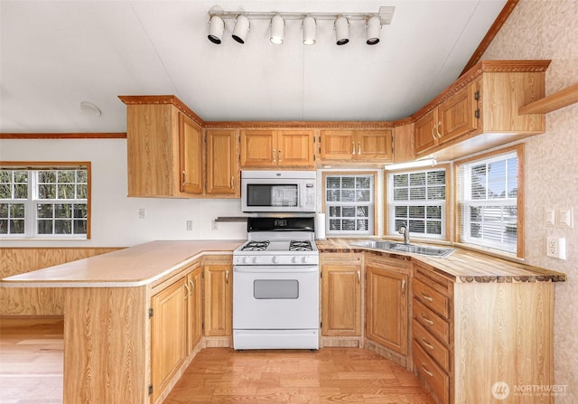 kitchen featuring white appliances, light wood-type flooring, crown molding, sink, and kitchen peninsula