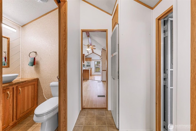 bathroom featuring toilet, ceiling fan, vaulted ceiling, ornamental molding, and vanity