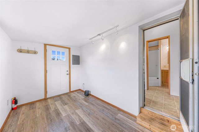 interior space featuring light wood-type flooring, electric panel, and track lighting