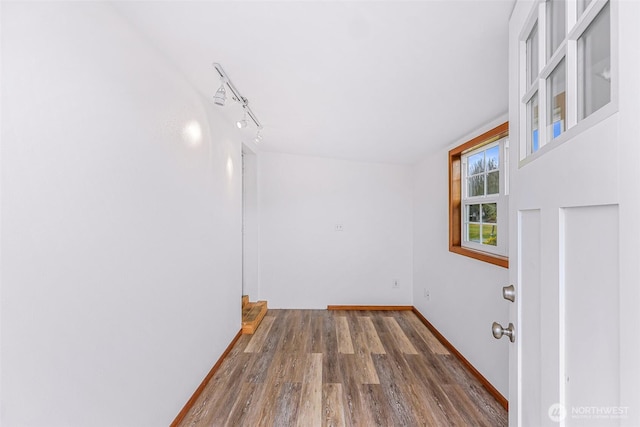 spare room featuring track lighting and wood-type flooring