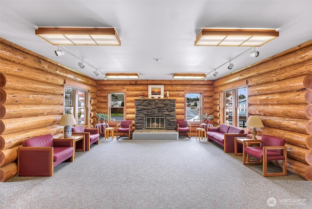 living room with track lighting, a stone fireplace, and carpet floors