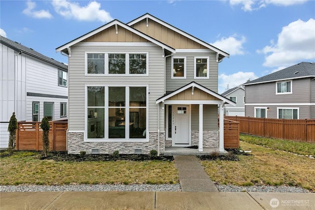 craftsman house with board and batten siding, stone siding, and fence