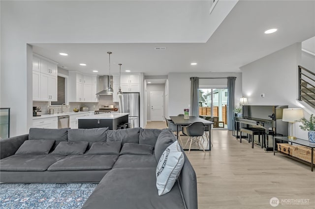 living room featuring light wood-type flooring, visible vents, and recessed lighting