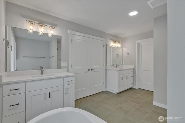 full bathroom featuring a freestanding bath, two vanities, and a sink