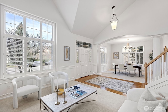 living room with arched walkways, a wainscoted wall, wood finished floors, ornate columns, and a decorative wall