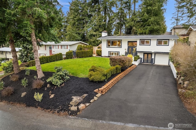 raised ranch featuring a front lawn and a garage