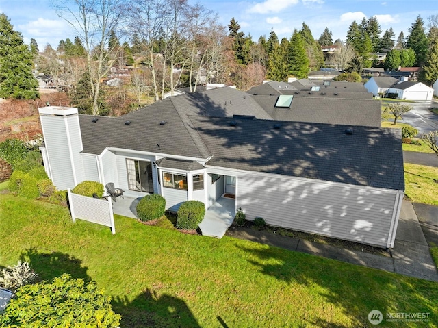 rear view of house with a patio, a shingled roof, a lawn, and fence