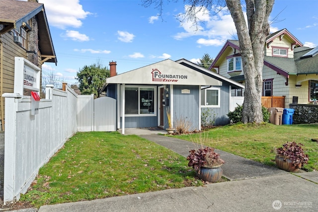 view of front of property with a chimney, a front yard, and fence