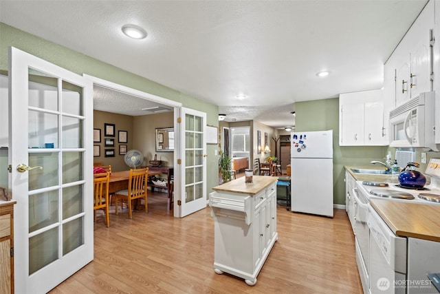 kitchen featuring white appliances, white cabinetry, wooden counters, french doors, and light wood-type flooring