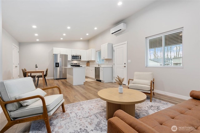 living room with a wall mounted air conditioner, light hardwood / wood-style flooring, and plenty of natural light