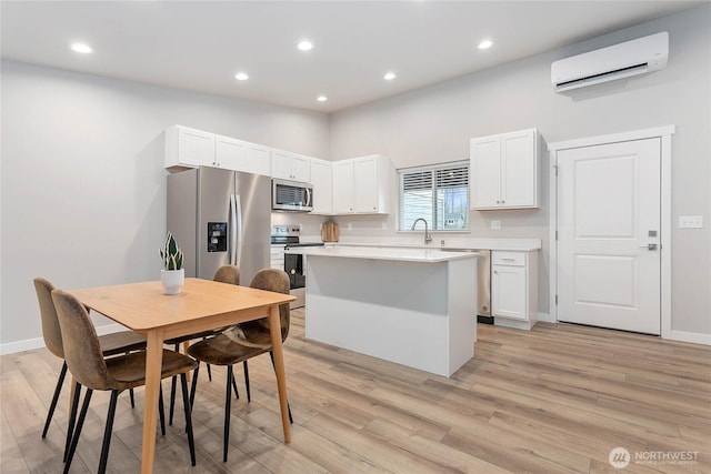 kitchen featuring an AC wall unit, white cabinetry, stainless steel appliances, a kitchen island, and sink