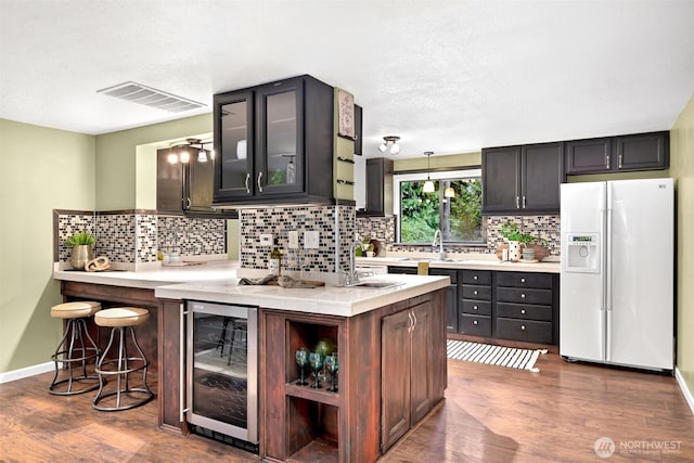 kitchen featuring dark brown cabinets, beverage cooler, dark hardwood / wood-style floors, and white fridge with ice dispenser