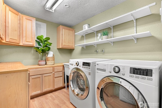 washroom with a textured ceiling, washer and dryer, cabinets, and light hardwood / wood-style floors